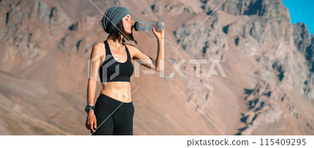 Sportive girl drinks water in the mountains. 115409295