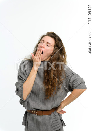 A young woman yawns covering her mouth with her hand. 115409393