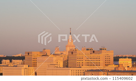 View of the building of Moscow State University (MSU) and the situation center of the Ministry of Defense in the rays of the dawn sun on a summer morning 115409602