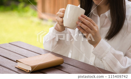 A young woman reading a book in an open cafe 115409742