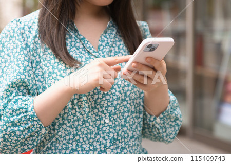 Young woman using a smartphone on the street 115409743