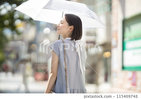 一位年輕女子撐著陽傘穿過城市 115409748