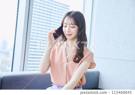 Woman making a phone call on the sofa in the office 115409845