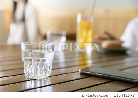 A well-worn water glass and smartphone in a cafe A well-worn water glass and smartphone in a cafe 115411578