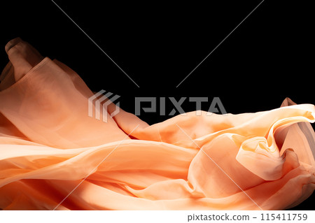Orange Organza fabric flying in curve shape, Piece of textile Orange Organza fabric throw fall in air. Black background isolated, dark shading environment 115411759