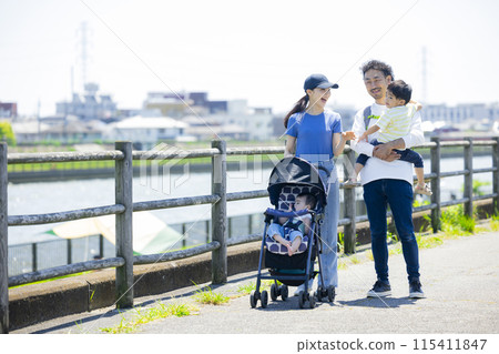 家長和孩子推著嬰兒車沿著河岸行走 家長和孩子推著嬰兒車沿著河岸行走 115411847