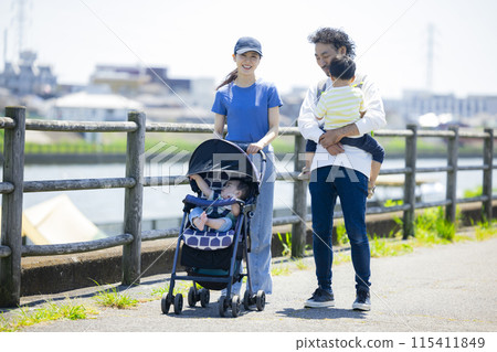 家長和孩子推著嬰兒車沿著河岸行走 家長和孩子推著嬰兒車沿著河岸行走 115411849