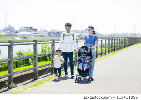 家長和孩子推著嬰兒車沿著河岸行走 115411859