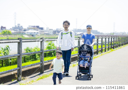 A parent and child walking along the river bank pushing a stroller 115411861