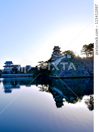 Early May morning: The silhouette of Imabari Castle shining against the sunlight. Its silhouette is also reflected in the moat. Early May morning: The silhouette of Imabari Castle shining against the sunlight. Its silhouette is also reflected in the moat. 115412097