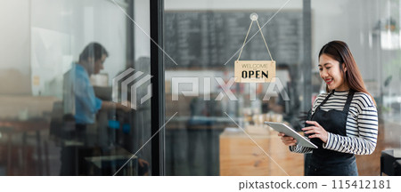 Smiling female barista using a digital tablet in a modern coffee shop with an open sign on the glass door. Busy cafe interior, small business concept. Smiling female barista using a digital tablet in a modern coffee shop with an open sign on the glass door. Busy cafe interior, small business concept. 115412181
