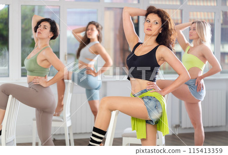 Putting foot hand on seat of chair, girl improvises, perform lap dance during group master class Putting foot hand on seat of chair, girl improvises, perform lap dance during group master class 115413359