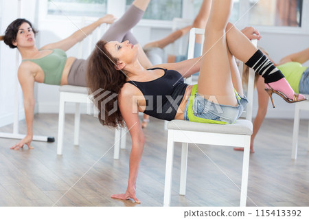 Dark-haired woman lying on chair during sass dance class in studio 115413392