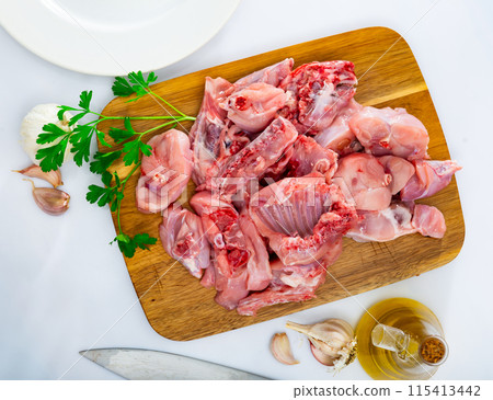 Chopped fresh raw rabbit with greens, garlic and spices on wooden cutting board Chopped fresh raw rabbit with greens, garlic and spices on wooden cutting board 115413442