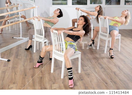 Group of women in high heels rehearsing dance while sitting on chair Group of women in high heels rehearsing dance while sitting on chair 115413484