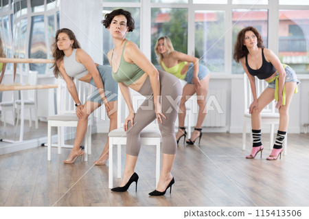 Group of women in high heels rehearsing dance while standing near chair 115413506