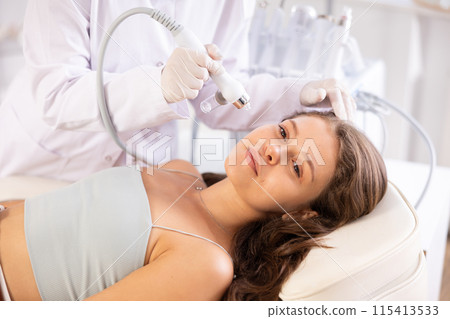Young girl undergoing facial procedure with atomized nutrients applying to skin 115413533