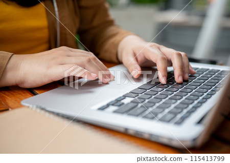 A close-up image of a woman working remotely, working on her laptop, typing on the keyboard. 115413799