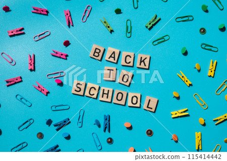 Educational greeting announcement for students and teacher. Saying BACK TO SCHOOL text on wooden blocks on creative vivid background with stationery supplies around. Concept of new school year 115414442