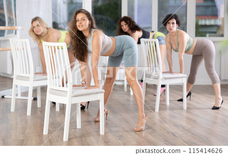 Active caucasian female dancer embodies passion and showcases creativity in high heels near chair at dance studio during group dance classes with young women Active caucasian female dancer embodies passion and showcases creativity in high heels near chair at dance studio during group dance classes with young women 115414626