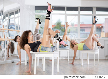 Girl coach shows combination of lap dance movements performed while lying on chair. 115414647