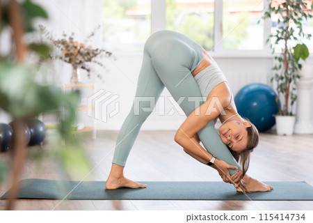 Experienced girl fitness club teacher performs parshvottanasana 115414734