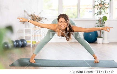 Experienced girl fitness club teacher performs prasarita padottanasana 115414742