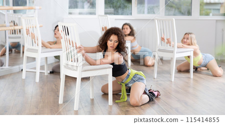 Brunette kneeling provocatively before chair during erotic dance at group class 115414855