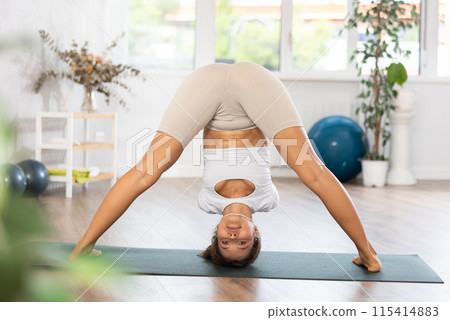 Woman exercising warrior one pose during yoga training in gym 115414883