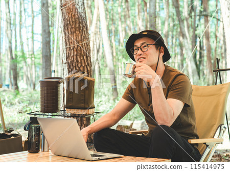 A man working remotely at a campsite (nomad work, telework, remote work) A man working remotely at a campsite (nomad work, telework, remote work) 115414975