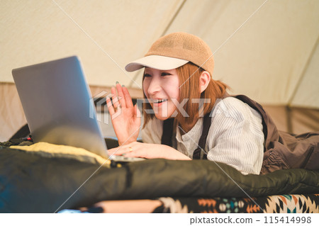 一名女露營者在營地使用電腦工作、視訊通話、直播。 一名女露營者在營地使用電腦工作、視訊通話、直播。 115414998