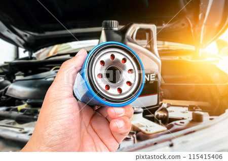 Engine oil filter is in the hands of the mechanic to be changed along with the engine oil Engine oil filter is in the hands of the mechanic to be changed along with the engine oil 115415406