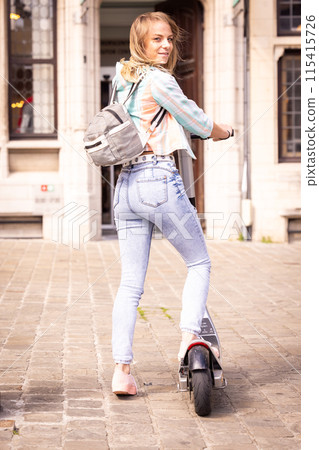 A young woman rides an electric scooter in the city center, enjoying urban lifestyle A young woman rides an electric scooter in the city center, enjoying urban lifestyle 115415726