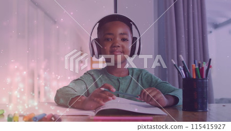 Image of lights over happy african american boy wearing headphones and doing homework Image of lights over happy african american boy wearing headphones and doing homework 115415927