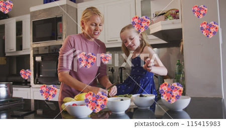 Image of flower hearts over caucasian mother and daughter cooking together 115415983