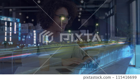 Image of smiling woman using laptop in cafe, over sped up traffic in city at night 115416699