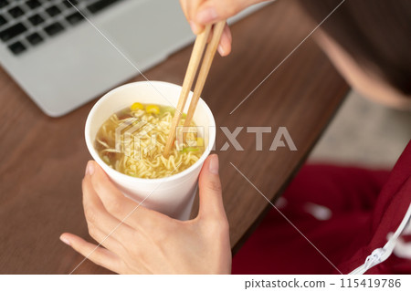 Woman eating cup ramen 115419786