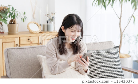 A woman looking at her smartphone in the living room 115420373