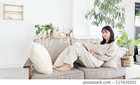 A woman reading a book on the sofa A woman reading a book on the sofa 115420391