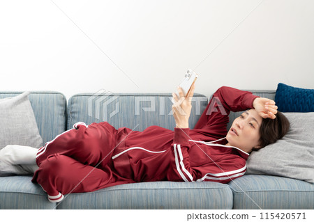 Woman looking at smartphone on sofa, stressed 115420571