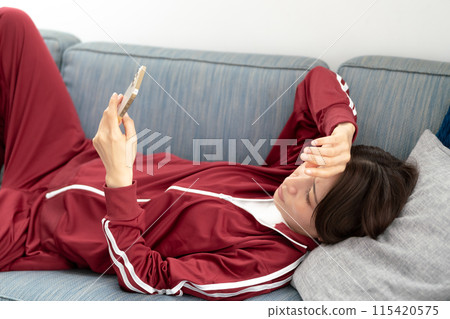 Woman looking at smartphone on sofa, stressed 115420575