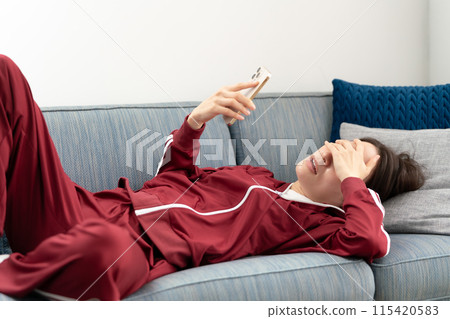 Woman looking at smartphone on sofa, stressed Woman looking at smartphone on sofa, stressed 115420583