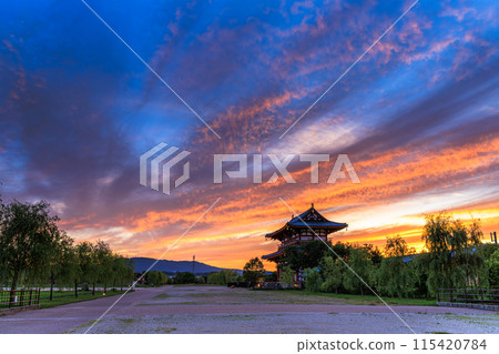 Evening view of the Suzakumon Square at the Heijo-kyo site in Nara: crimson clouds spreading across the sky and the Suzakumon Gate ④ Evening view of the Suzakumon Square at the Heijo-kyo site in Nara: crimson clouds spreading across the sky and the Suzakumon Gate ④ 115420784
