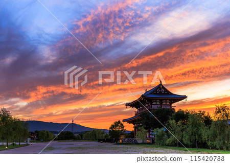 Evening view of the Suzakumon Square at the Heijo-kyo site in Nara: crimson clouds spreading across the sky and the Suzakumon Gate 5 Evening view of the Suzakumon Square at the Heijo-kyo site in Nara: crimson clouds spreading across the sky and the Suzakumon Gate 5 115420788