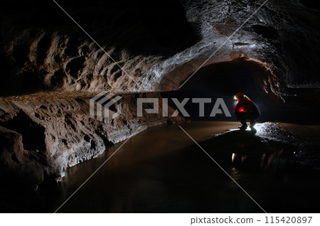 Cave explorer, spelunker, archeologist stuydying underground passage Cave explorer, spelunker, archeologist stuydying underground passage 115420897