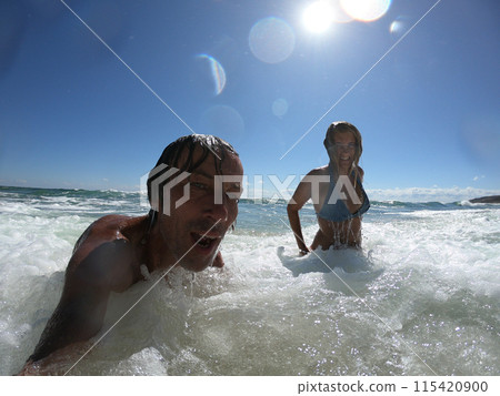 Powerful ocean waves splashing funny couple Powerful ocean waves splashing funny couple 115420900