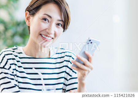 A middle-aged woman who operates a smartphone at a cafe. 115421026