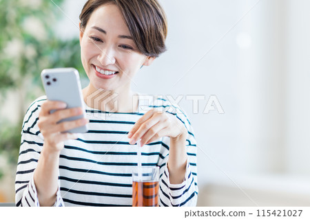 A middle-aged woman who operates a smartphone at a cafe. A middle-aged woman who operates a smartphone at a cafe. 115421027