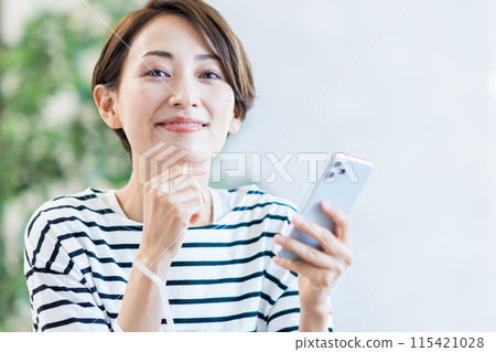A middle-aged woman who operates a smartphone at a cafe. A middle-aged woman who operates a smartphone at a cafe. 115421028