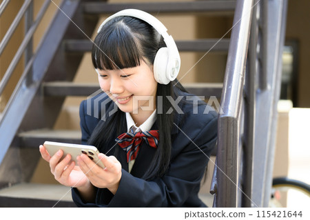 High school girl listening to music headphones High school girl listening to music headphones 115421644
